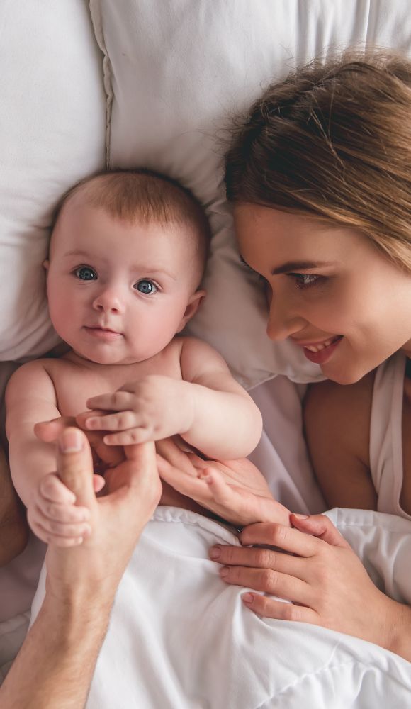szczęśliwa para leżąca z niemowlakiem na łóżku poczętym metodą in vitro